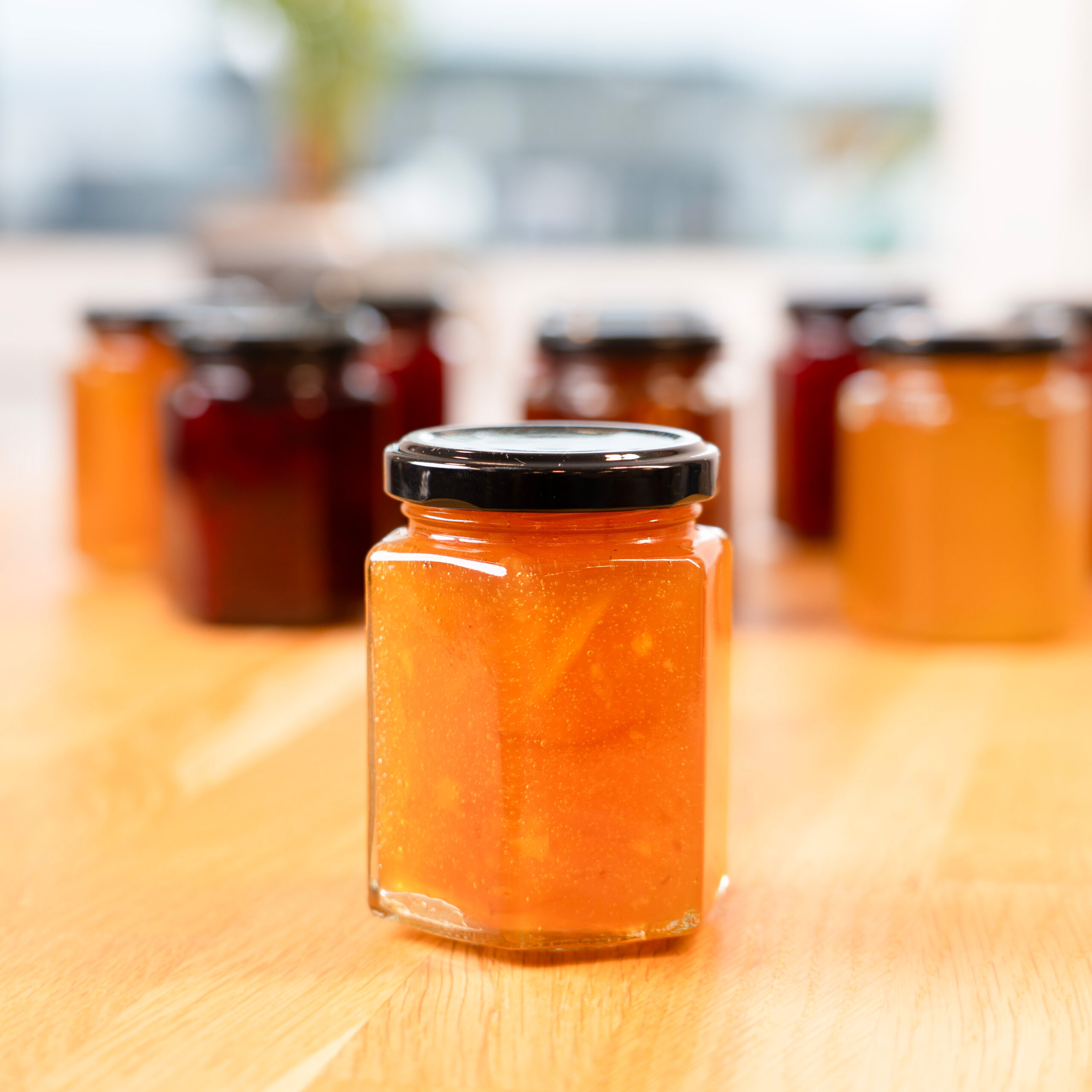 Frisches Glas Schwarzwälder Konfitüre im Vordergrund, umgeben von mehreren Marmeladengläsern im Hintergrund – Symbol für handgemachte Qualität und echten Genuss.